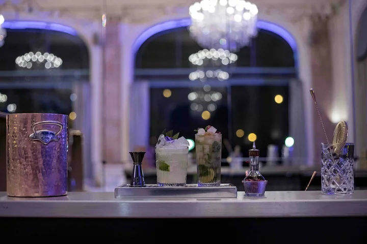 Bar mobile L'Orchestre dressé dans un grand salon à lustre de cristal et fenêtres cintrées, ambiance bleutée du soir