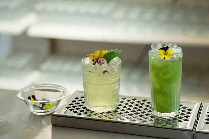 Deux cocktails verts garnis de fleurs comestibles sur égouttoir inox, lumière douce